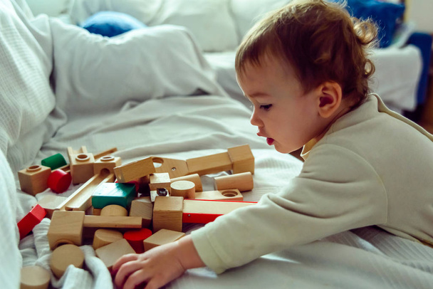 Bebê se diverte selecionando cubos de madeira para brincar com eles e desenvolver
 - Foto, Imagem