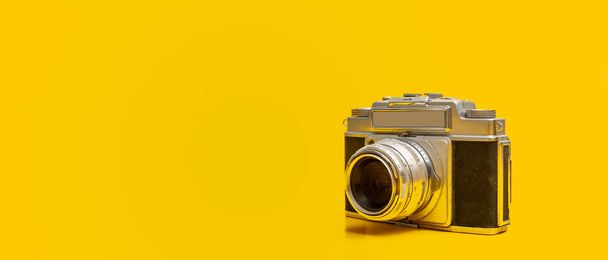 Close-up foto van oude vintage camera op gele achtergrond met kopieerruimte - Foto, afbeelding