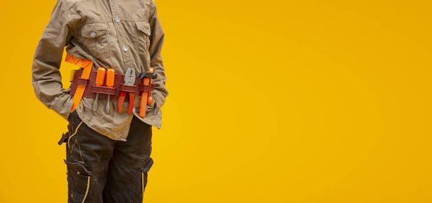 Pracownik z narzędziami budowlanymi na żółtym tle, koncepcja dnia pracy - Zdjęcie, obraz