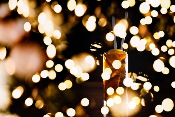 Cuba libre cocktail in a tall glass with festive bokeh lights - Fotoğraf, Görsel