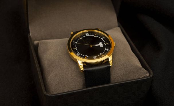 Розкішний золотий ручний годинник у подарунковій коробці на чорному тлі
 - Фото, зображення
