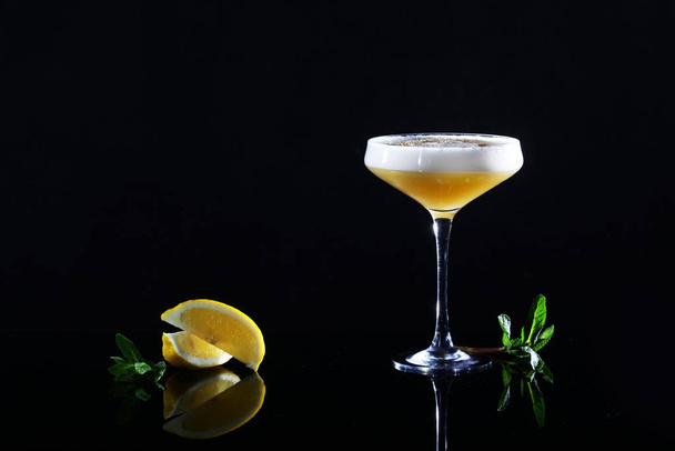 Alcoholic cocktail of yellow color in an elegant glass on a high leg. Copy space. - 写真・画像