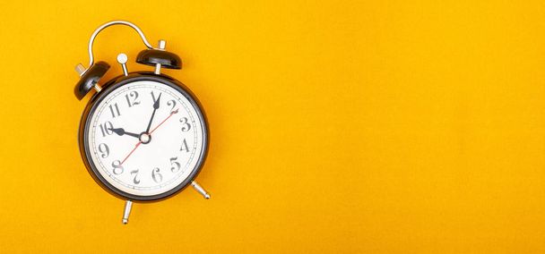 Reloj despertador de estilo vintage en banner de fondo amarillo con espacio de copia
 - Foto, imagen