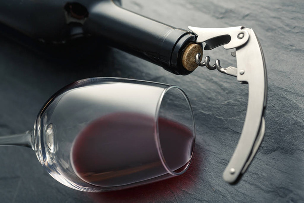 Roestvrij kurkentrekker in een kurk van fles hals en wijnglas met - Foto, afbeelding