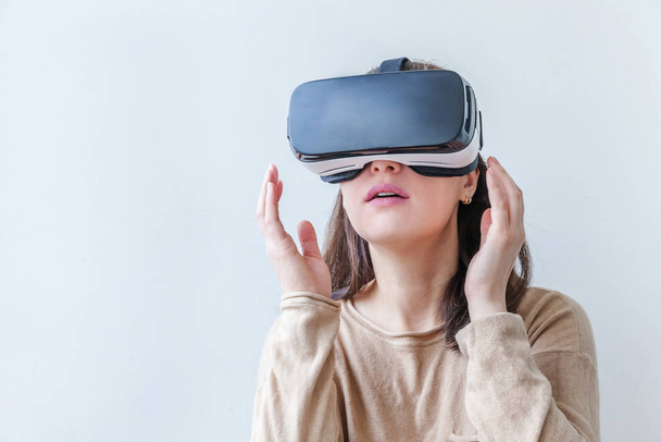 Улыбнитесь молодой женщине в шлеме виртуальной реальности VR очки на белом фоне. Смартфон с очками виртуальной реальности. Технологии, технологии, хай-тек, концепция видеоигр. - Фото, изображение