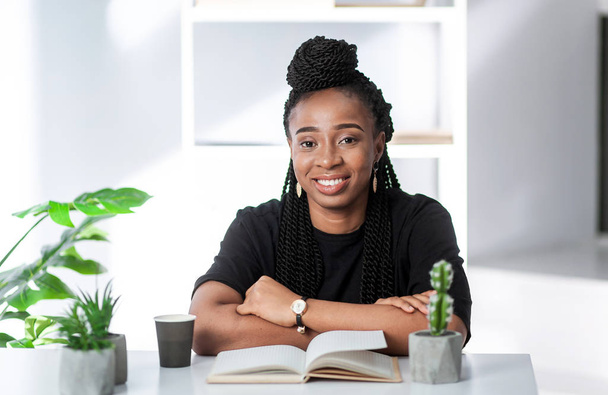 Αφρο-Αμερικανίδα που κάθεται στο γραφείο στο τραπέζι. Επιχειρηματίας στο χώρο εργασίας. - Φωτογραφία, εικόνα