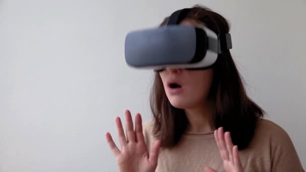 Sonríe mujer joven usando realidad virtual gafas VR casco auriculares sobre fondo blanco. Smartphone con gafas de realidad virtual. Tecnología, simulación, alta tecnología, concepto de videojuego - Metraje, vídeo