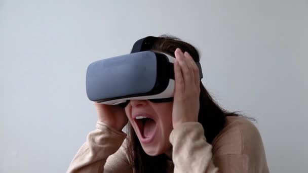 Mosolyogj fiatal nő visel virtuális valóság VR szemüveg sisak fejhallgató fehér háttérrel. Okostelefon használata virtuális valóság szemüveg. Technológia, szimuláció, hi-tech, videojáték koncepció - Felvétel, videó