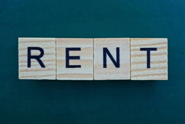 word rent made from wooden gray letters lies on a green background - Foto, Imagen