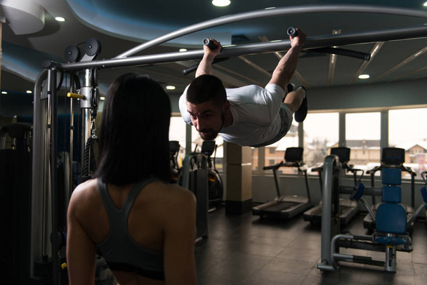 Man Doing Pull-Ups Exercises With Personal Trainer - Foto, imagen