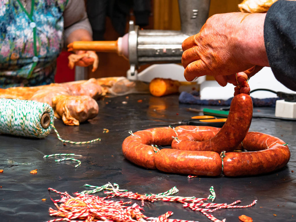 Femmes qui travaillent attacher des saucisses à ficelle rouge avec corde
 - Photo, image