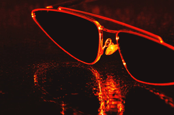 Dark retro eyewear glasses object close up on water drops in brown evening light - Photo, Image