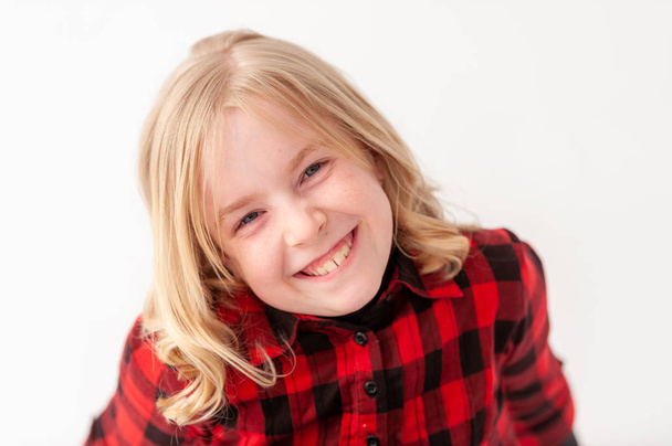 Φωτογραφία ενός νεαρού χαμογελαστού ξανθού κοριτσιού πριν την εφηβεία σε λευκό φόντο στούντιο - Φωτογραφία, εικόνα