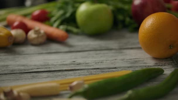 Erntehelfer rollen orange auf einem rustikalen Holztisch. Vegetarisches Ernährungskonzept. - Filmmaterial, Video