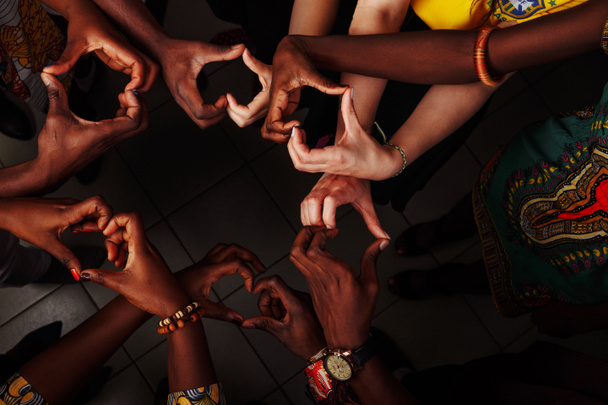 Hands in the form of heart of happy group of multinational African, latin american and european people which stay together in circle - Photo, Image