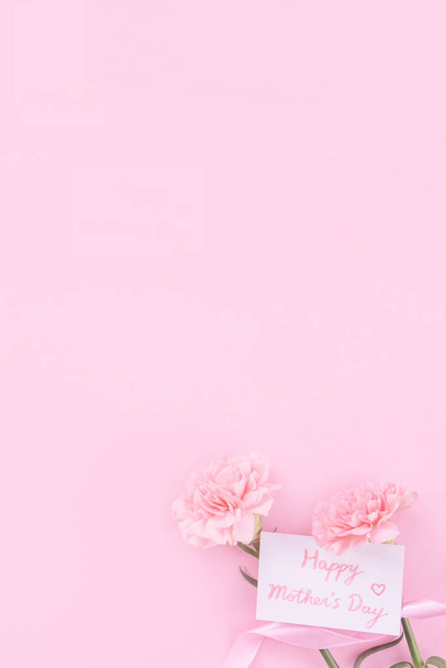 Beautiful, fresh elegant carnation flower bouquet with white greeting thanks gift card isolated on bright pink color background, top view, flat lay concept. - Foto, Bild