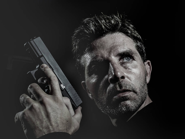 closeup portrait of serious and attractive hitman or special agent man holding gun isolated on black background in secret service Hollywood style movie and cinematic lighting - Foto, immagini
