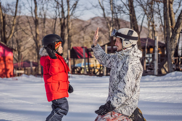 Dad teaches son snowboarding. Activities for children in winter. Childrens winter sport. Lifestyle - Foto, Imagen