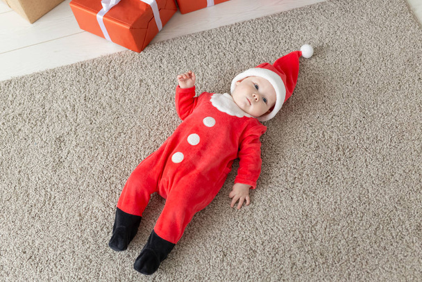 Güzel küçük bebek Noel 'i kutluyor. Yeni yıl tatili. Noel kostümü içindeki komik bebek ve Noel Baba şapkası, üst manzara - Fotoğraf, Görsel