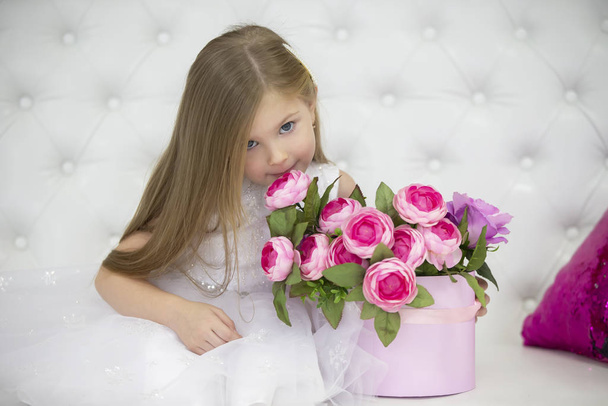 Beautiful child girl sniffing flowers. - Zdjęcie, obraz