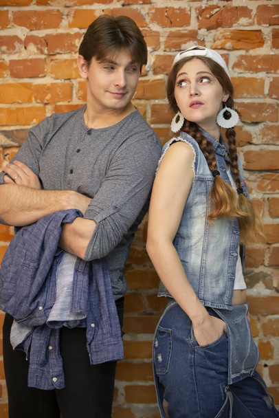 Vertikale Kerle und Mädchen stehen vor einer Ziegelmauer. junges Paar in Jeans-Kleidung - Foto, Bild