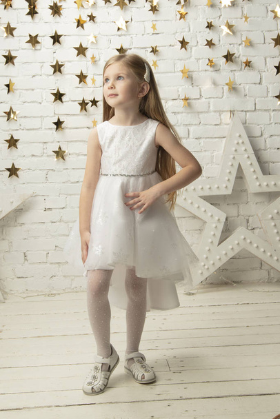 Beyaz elbiseli, dikey olarak zarif bir çocuk. Küçük kız modeli. - Fotoğraf, Görsel