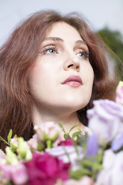 Retrato vertical de uma bela mulher de cabelos compridos com um buquê de flores
 - Foto, Imagem