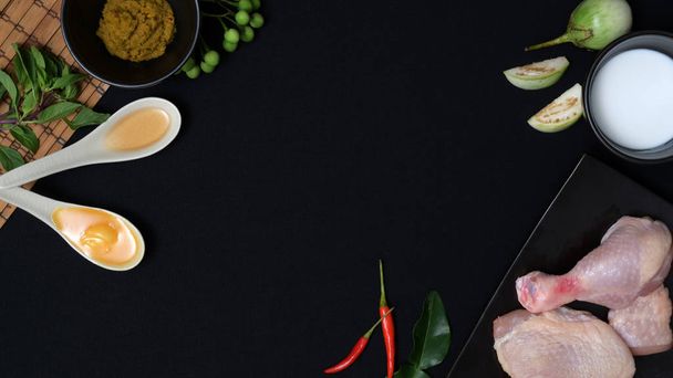 Overhead shot of Thai food ingredients and herbs for chicken green curry on black desk  background - Foto, afbeelding