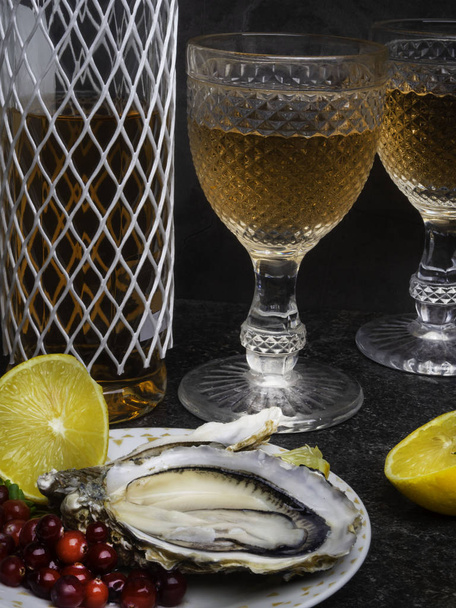 Fresh oysters in plate, wine or champagne bottle, lemon, cranberries. Food background - 写真・画像