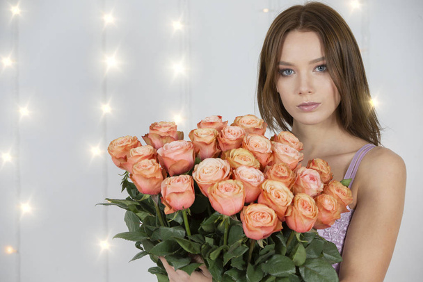 Πορτρέτο ενός νεαρού όμορφου κοριτσιού με μπουκέτο τριαντάφυλλα - Φωτογραφία, εικόνα