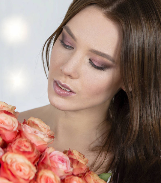 Beautiful face of the model and with a bouquet of roses. Woman with flowers. - Foto, Bild