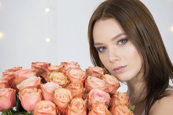 Beautiful face of the model and with a bouquet of roses. Woman with flowers. - Фото, зображення
