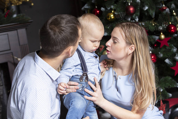 Familia en Navidad. Mamá papá e hijo en el árbol de Navidad
 - Foto, imagen