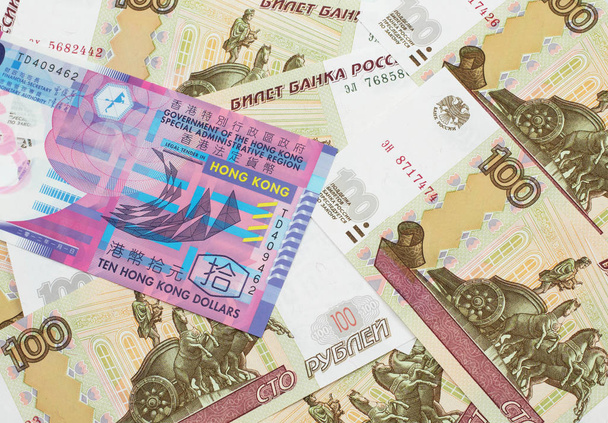 Зображення барвистого гонконгського банкноту в десять доларів на макросовому ліжку російськими банкнотами в сто рублів. - Фото, зображення