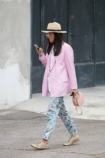 Woman with pink jacket and floral trousers before Arthur Arbesser fashion show, Milan Fashion Week street style  - Foto, immagini