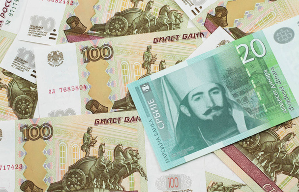 A close up of a green and white, twenty Serbian dinar bank note on a background of Russian one hundred ruble bank notes - Photo, Image
