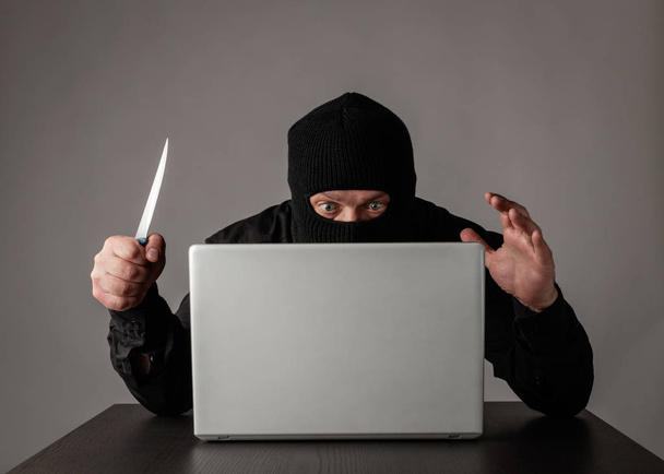 Hacker con máscara usando un portátil
. - Foto, imagen