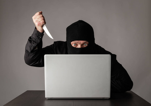 Hacker in mask using a laptop. - Photo, Image