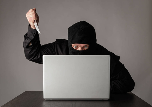 Hacker in mask using a laptop. - Φωτογραφία, εικόνα