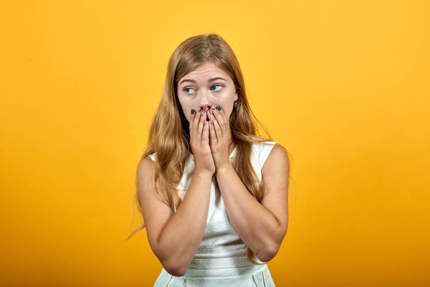 Przerażona młoda kobieta zakrywająca usta dłońmi, wyglądająca na przerażoną - Zdjęcie, obraz