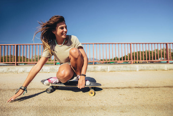 Jovem mulher esportiva montando no skate na estrada. - Foto, Imagem