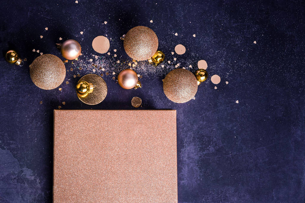 Composición navideña. Concepto de regalo de Navidad con decoraciones doradas, bolas, purpurina sobre un fondo azul oscuro. Copiar espacio Minimalismo plano laico
 - Foto, Imagen
