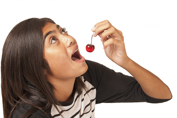 Joven chica polinesia comiendo una cereza
 - Foto, Imagen