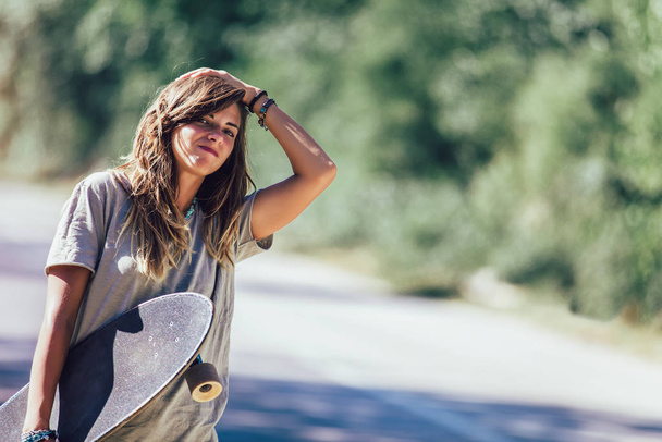 Skateboard κορίτσι hitchhiking και να σταματήσει το αυτοκίνητο στην ύπαιθρο δρόμο - Φωτογραφία, εικόνα
