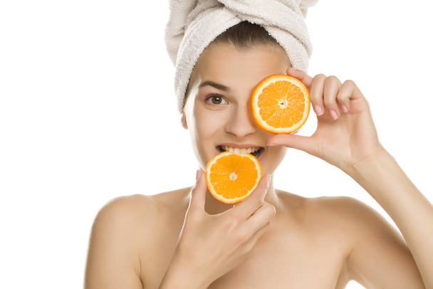 Portret van jonge shirtles mooie vrouw eten van een sinaasappel op witte achtergrond - Foto, afbeelding