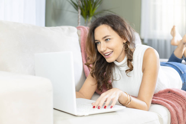 Young woman using laptop on sof - Valokuva, kuva