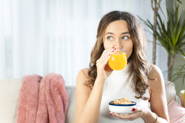 Mısır gevreği ve portakal suyuyla kahvaltı eden bir kadın. - Fotoğraf, Görsel