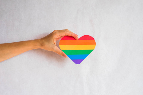 Woman holds in hands a heart in the colors of the rainbow. Young beautiful girl. LGBT history month. Pride Month. Lesbian Gay Bisexual Transgender. LGBT flag. Love, human rights, tolerance. LGBTQ+ - Fotó, kép