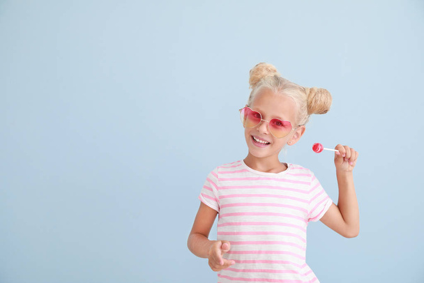 Cute little girl with lollipop on color background - Foto, Bild