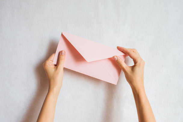 Woman holds in hand paper envelope. New mail, message. Postal service. Young girl want send or receive letter. Blank envelope, empty space. People communication concept. Envelope mockup closeup - Fotoğraf, Görsel